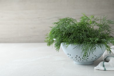 Fresh dill in colander on white table, space for text