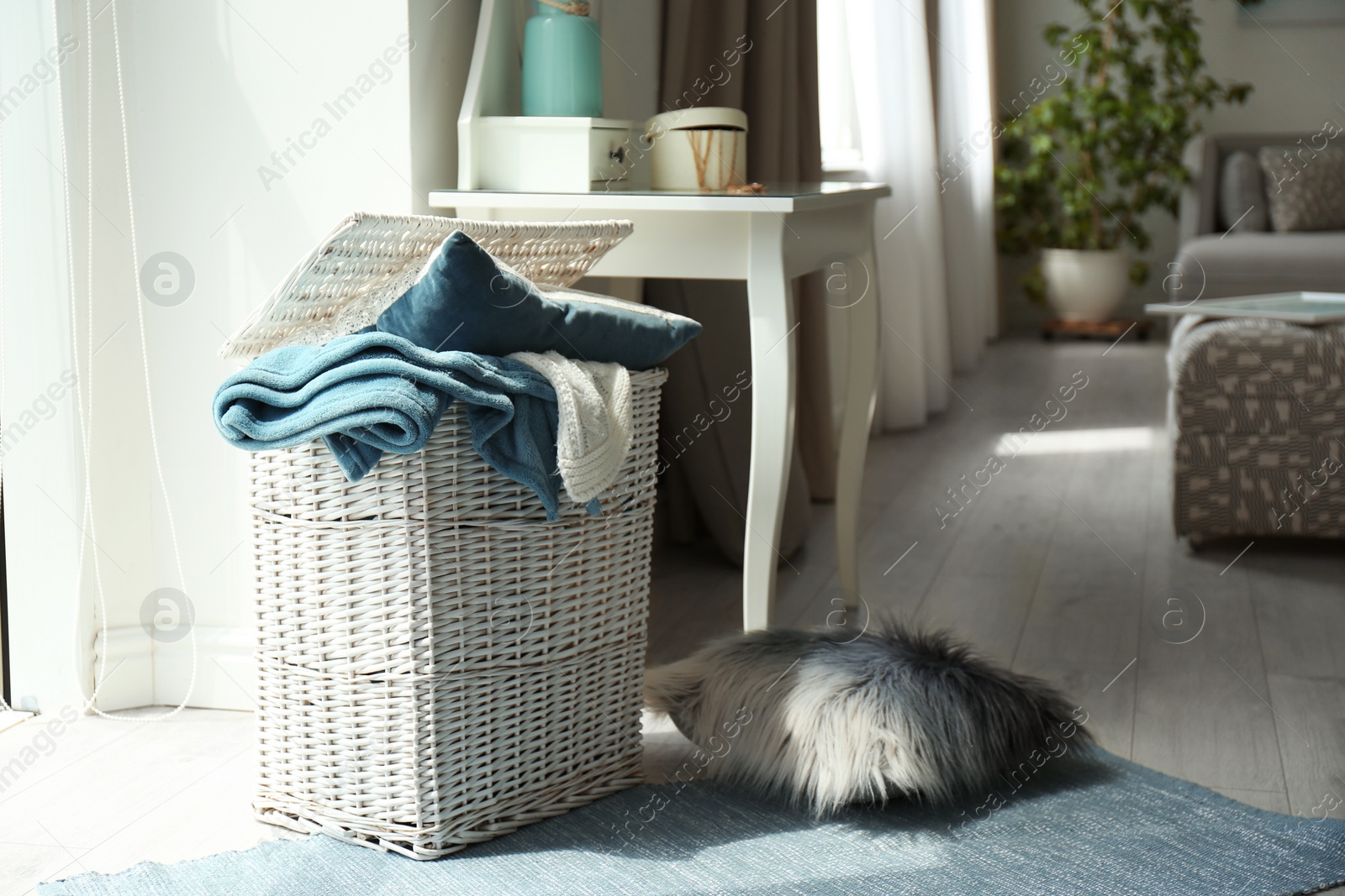 Photo of Basket with blankets and pillow near in light room