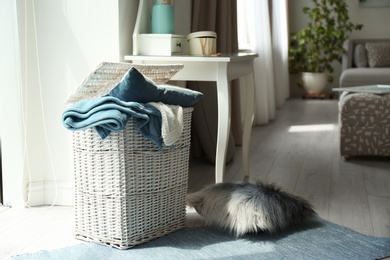 Photo of Basket with blankets and pillow near in light room