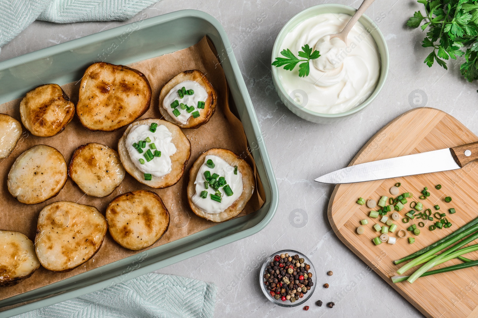 Photo of Sour cream dressing and delicious potato wedges on light grey table, flat lay