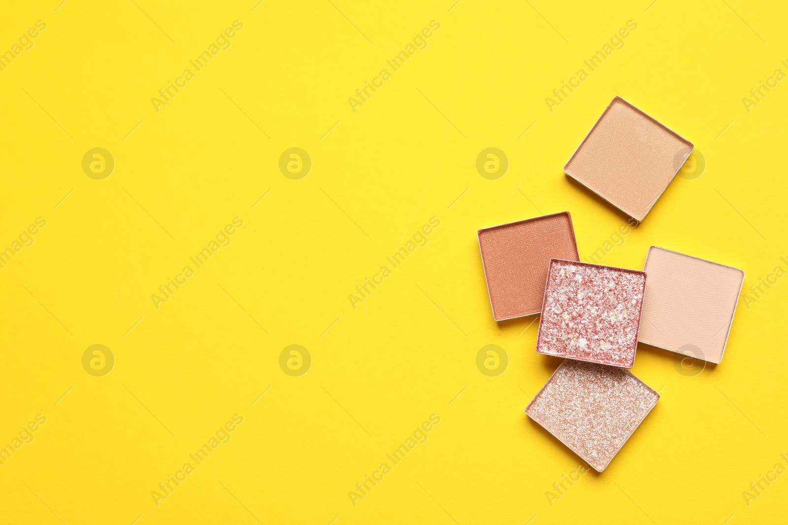 Photo of Beautiful eye shadow refill pans on yellow background, flat lay. Space for text