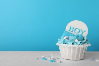 Photo of Baby shower cupcake with Boy topper on white table against light blue background, space for text