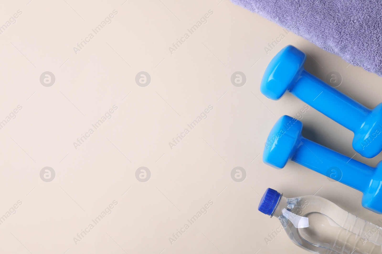 Photo of Vinyl dumbbells, towel and bottle of water on color background, flat lay. Space for text