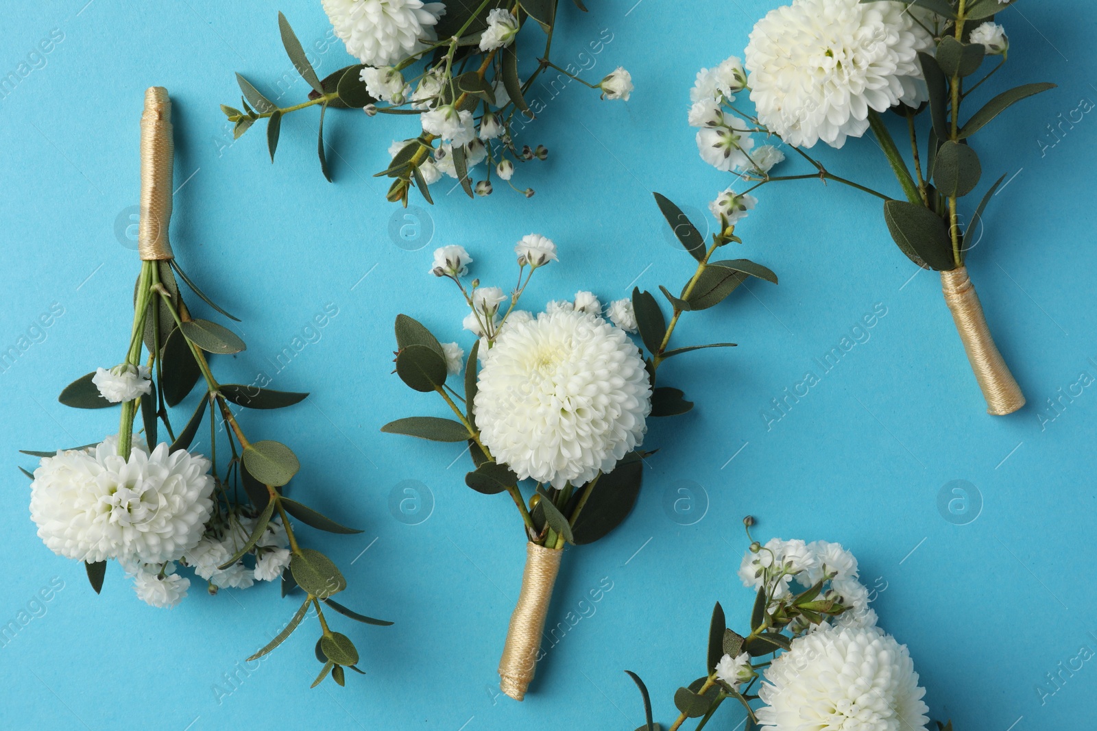 Photo of Many stylish boutonnieres on light blue background, flat lay