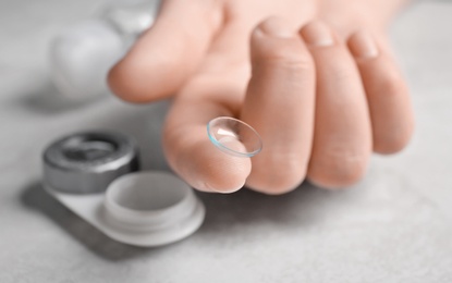 Photo of Woman holding contact lens over table, closeup