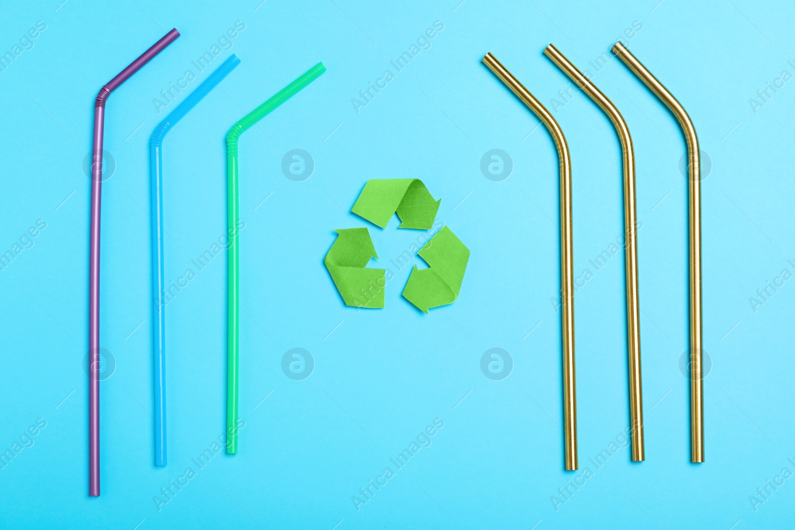 Photo of Recycling symbol, plastic and metal drinking straws on light blue background, flat lay