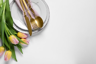 Stylish table setting with cutlery and tulips on white background, flat lay. Space for text