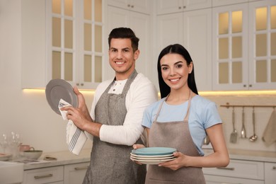 Photo of Happy couple with clean dishes in kitchen