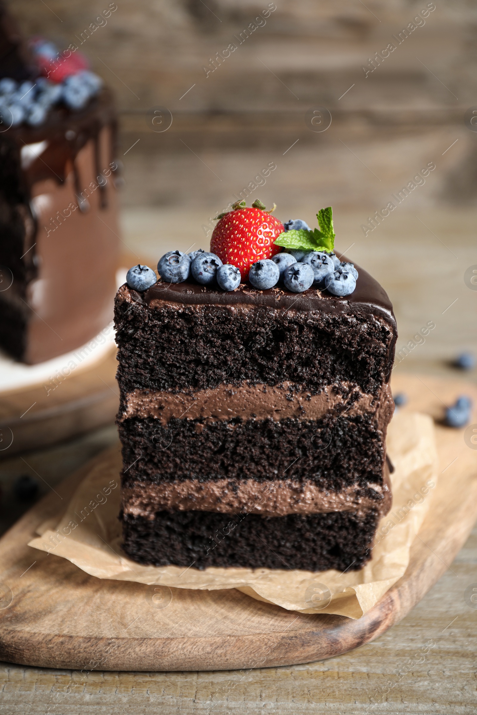 Photo of Piece of delicious chocolate cake decorated with fresh berries on wooden table