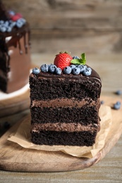 Piece of delicious chocolate cake decorated with fresh berries on wooden table