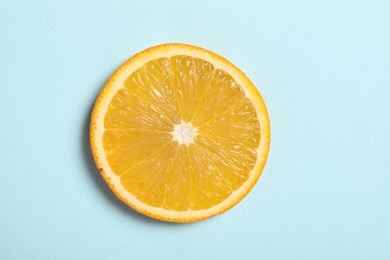 Photo of Slice of juicy orange on light blue background, top view