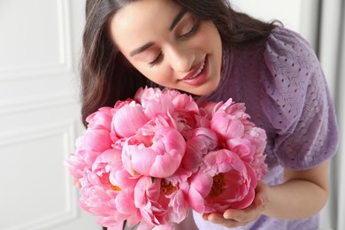 Photo of Young woman near bouquet of pink peonies indoors, closeup
