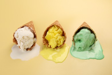 Photo of Melted ice cream in wafer cones on pale yellow background