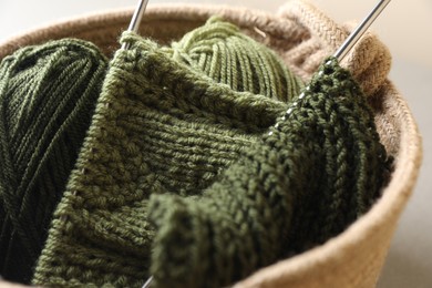 Green knitting, needles and soft yarns on light background, closeup