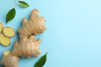 Photo of Fresh ginger with green leaves on pale light blue background, flat lay. Space for text
