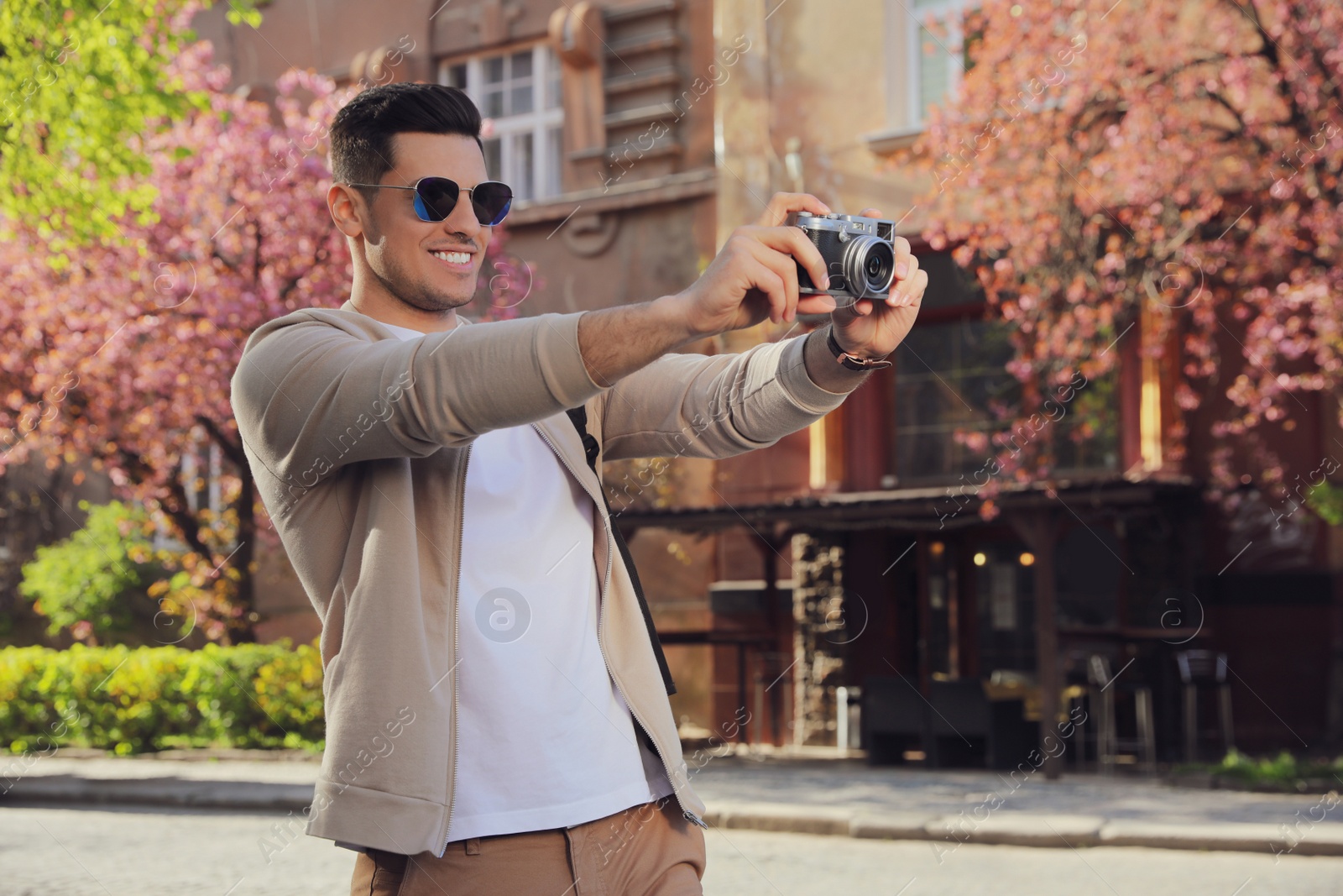 Photo of Happy male tourist with camera on city street