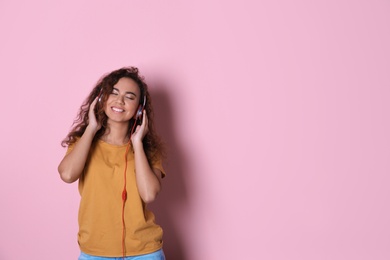 Photo of African-American girl listening to music with headphones on color background, space for text