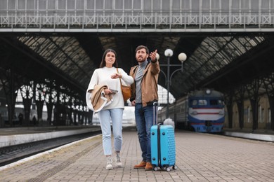 Photo of Being late. Worried couple with suitcase waiting at train station