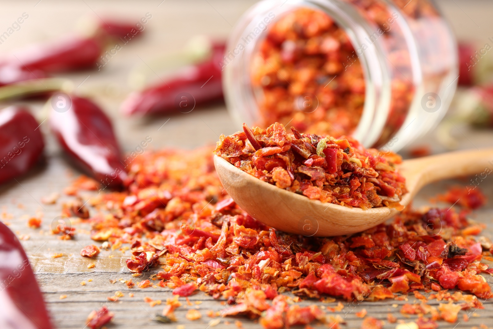 Photo of Chili pepper flakes and pods on wooden table, closeup. Space for text