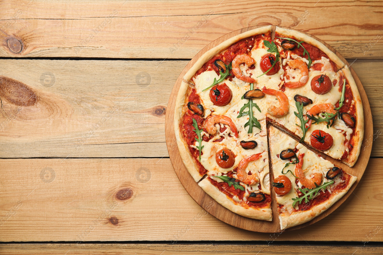 Photo of Delicious seafood pizza on wooden table, top view. Space for text