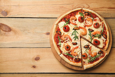 Delicious seafood pizza on wooden table, top view. Space for text