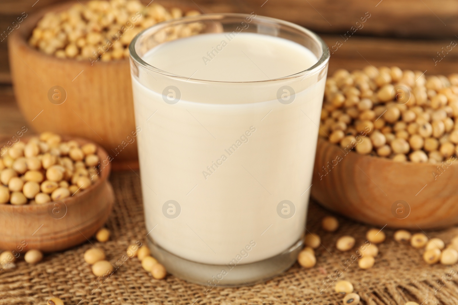 Photo of Glass with fresh soy milk and grains on wooden table, closeup