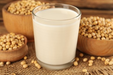 Glass with fresh soy milk and grains on wooden table, closeup