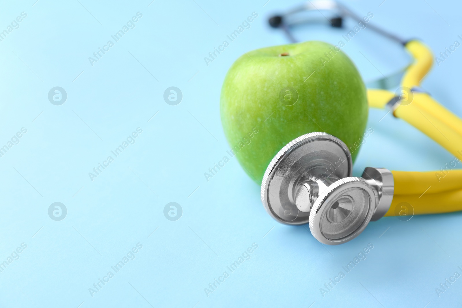 Photo of Stethoscope and apple on color background. Medical equipment