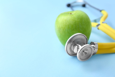 Stethoscope and apple on color background. Medical equipment