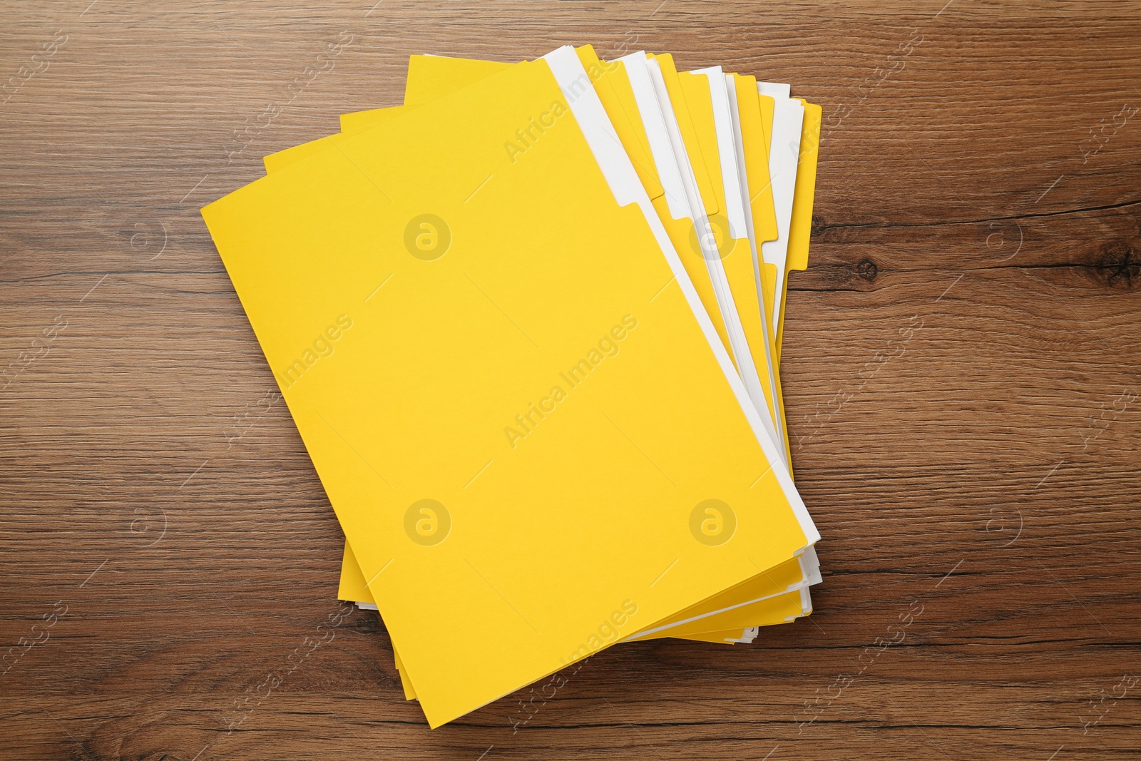 Photo of Yellow files with documents on wooden table, top view