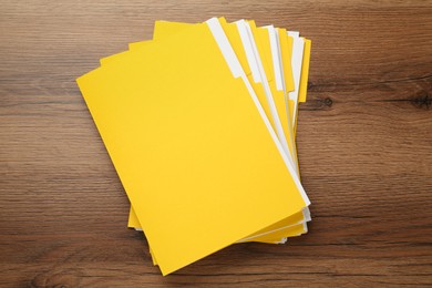 Yellow files with documents on wooden table, top view