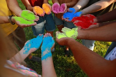 Photo of Friends with colorful powder dyes outdoors, closeup. Holi festival celebration