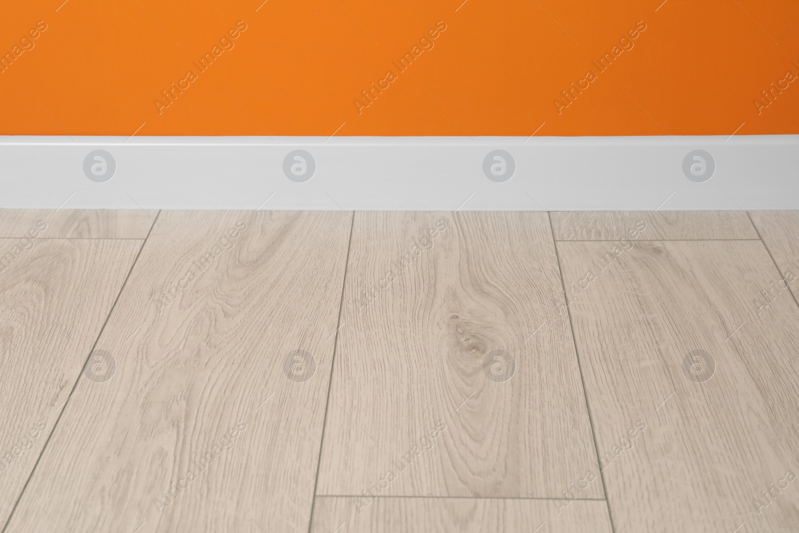 Photo of White plinth on laminated floor near orange wall indoors