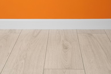 White plinth on laminated floor near orange wall indoors