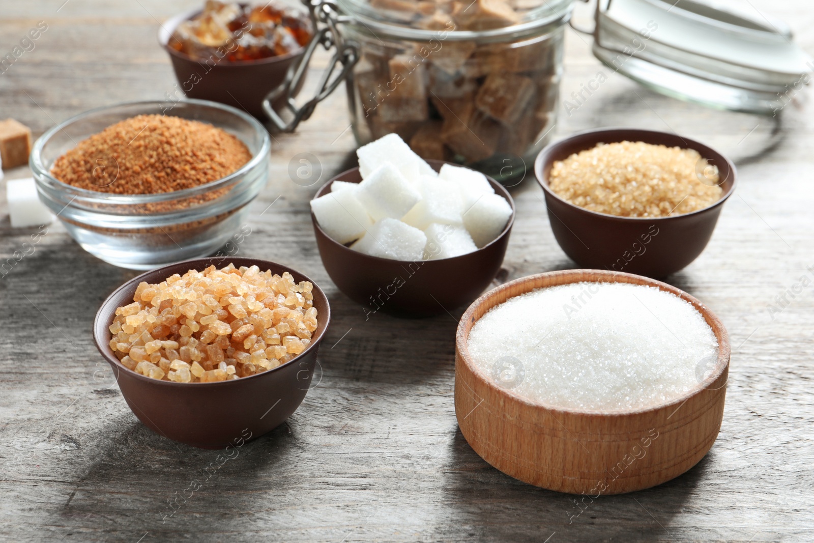 Photo of Various kinds of sugar in bowls on wooden background