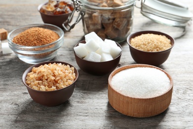 Various kinds of sugar in bowls on wooden background