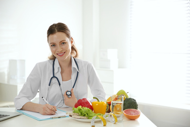 Photo of Nutritionist working at desk in office. Space for text