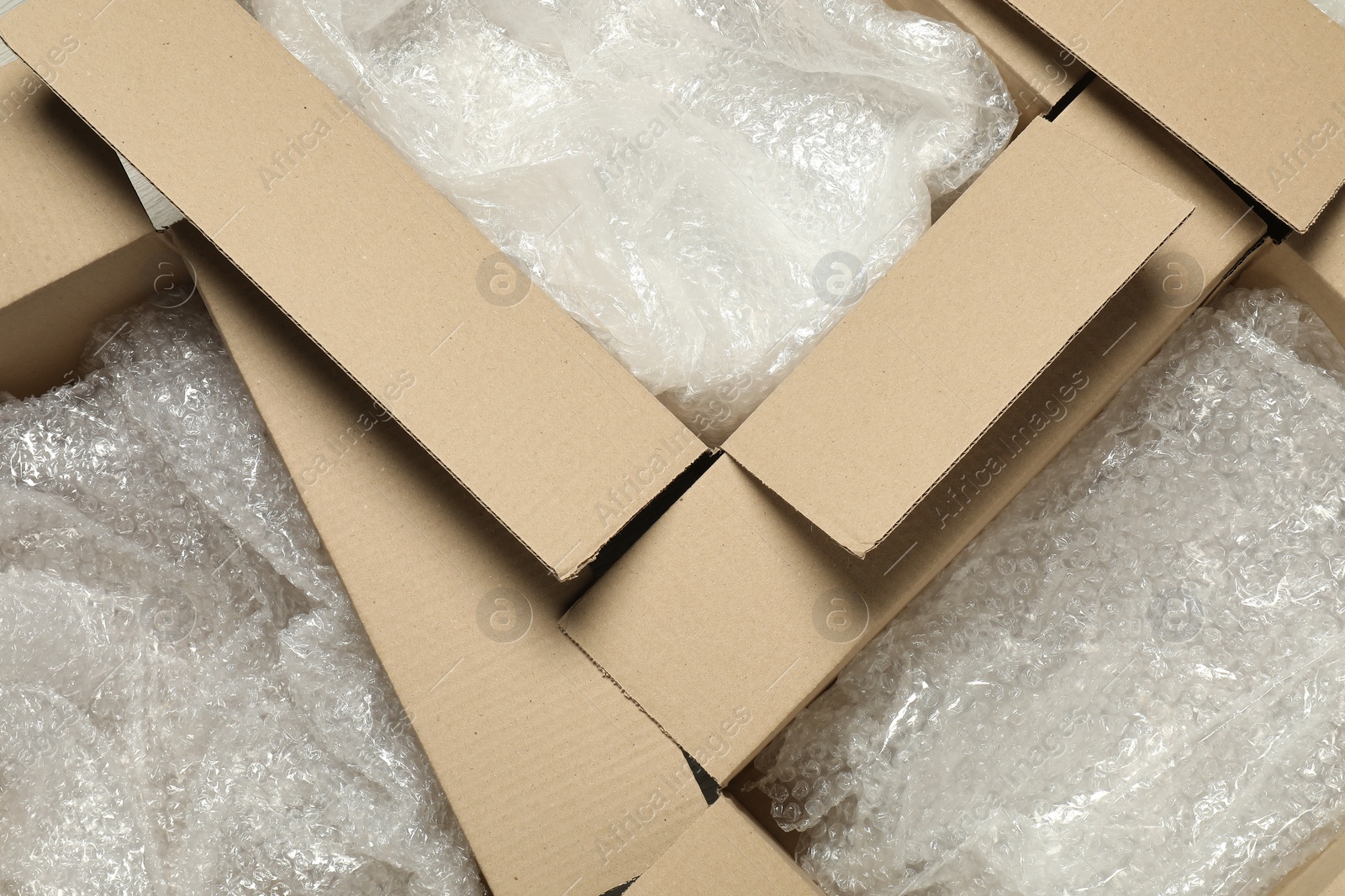 Photo of Many open cardboard boxes with bubble wrap as background, top view