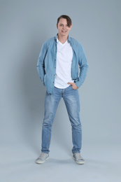 Photo of Young man in stylish jeans on grey background