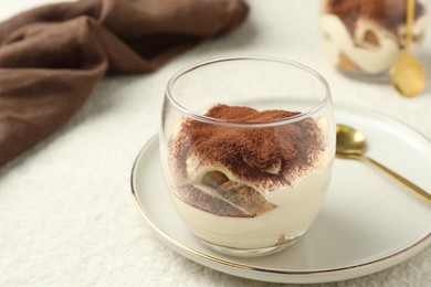 Delicious tiramisu in glass on white table, closeup. Space for text