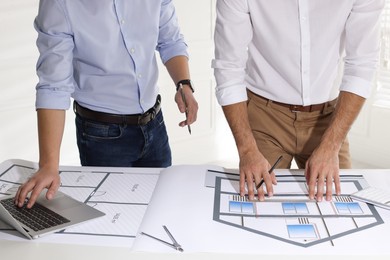 Architects working with construction drawings at table in office, closeup