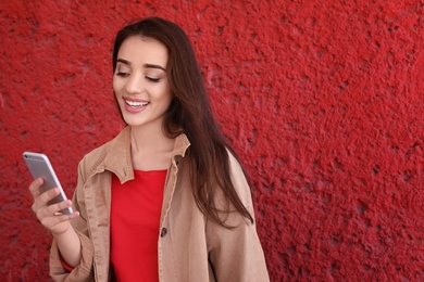 Photo of Young woman using mobile phone on color background