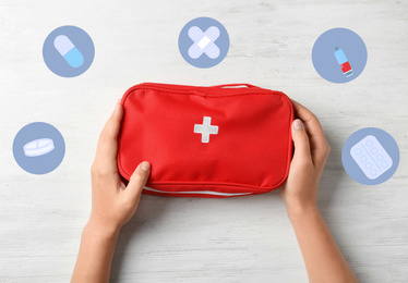 Woman holding first aid kit on wooden background, top view