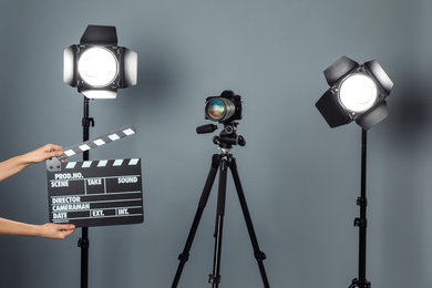 Photo of Woman with clapperboard near video camera in studio, closeup