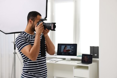 Photo of Young professional photographer taking picture in modern photo studio, space for text