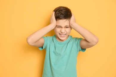 Photo of Little boy suffering from headache on color background