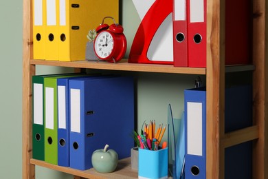 Photo of Colorful binder office folders and stationery on shelving unit indoors
