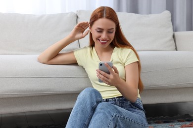 Happy young woman having video chat via smartphone at home