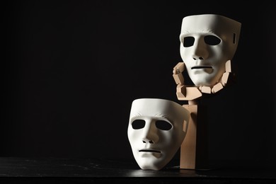 Photo of Wooden mannequin hand and plastic masks on black background, space for text. Theatrical performance