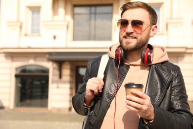 Happy young man with coffee on city street in morning